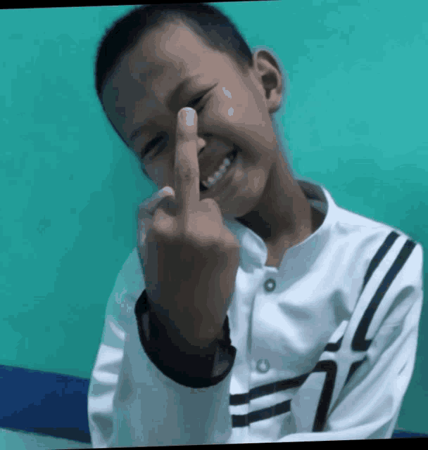 a young boy is giving the middle finger and smiling