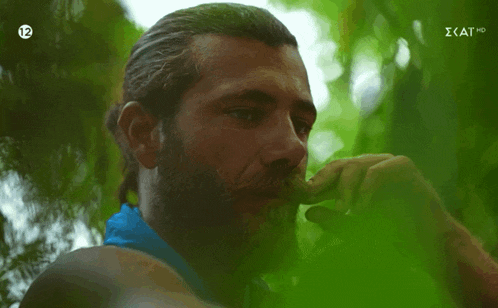 a man with a beard and a blue scarf around his neck has the number 12 on his chest
