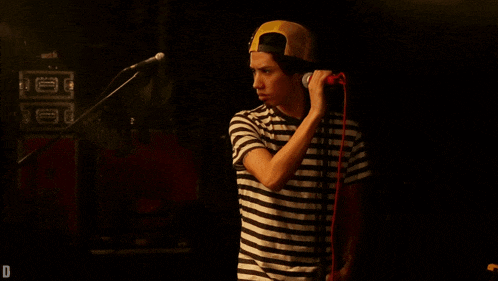 a man singing into a microphone with a hat that says grateful dead