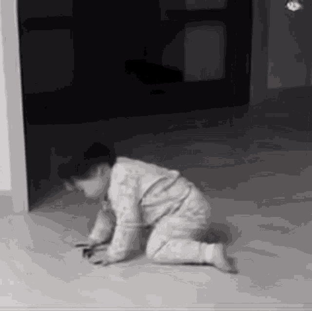 a baby is crawling on the floor in a dark room .