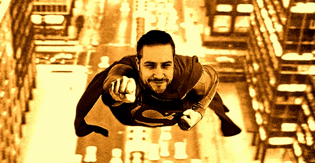 a man in a superman costume is flying through the air pointing at the camera
