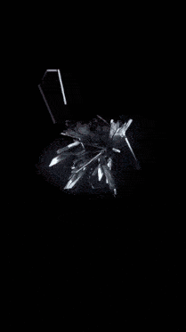 a black background with a lot of pieces of glass flying in the air
