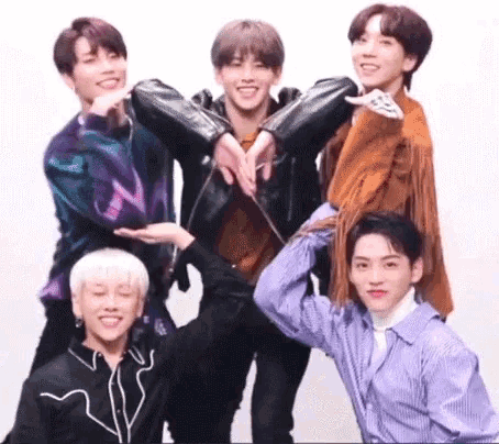 a group of young men are posing for a picture while making a heart shape with their hands .