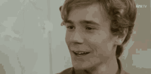 a close up of a young man with blonde hair smiling .