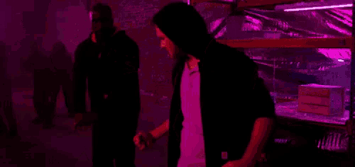 a man in a hoodie is standing in a dark room