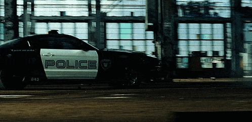 a black and white police car is parked in front of a garage