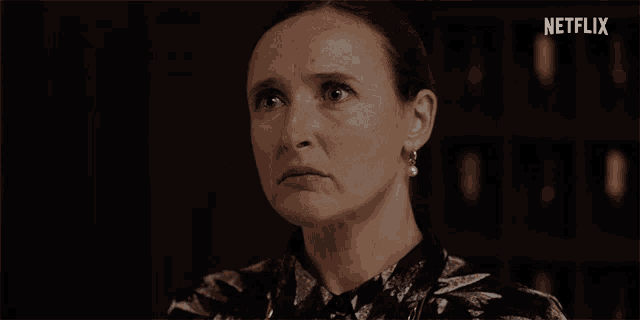 a woman with a pearl earring looks at the camera with a netflix logo in the background