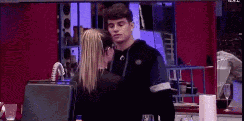 a man and a woman are hugging in a kitchen .