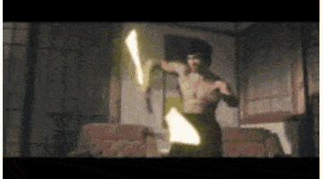 a man without a shirt is holding a sword in a dark room .