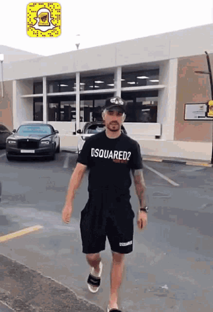a man wearing a black shirt that says dsquared2 is walking down the street