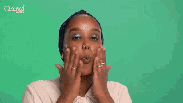 a woman is washing her face with a crowned ladies ad in the background .