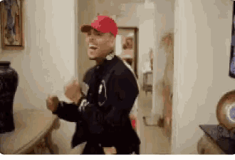 a man wearing a red hat is dancing in a room .