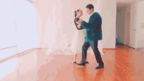 a man and a woman are dancing in an empty room with a wooden floor .