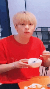 a man is sitting at a table eating food with chopsticks .