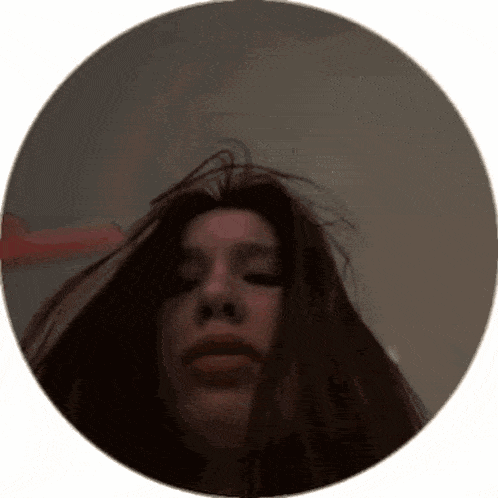 a woman 's face is visible in a circle with her hair blowing in the wind .