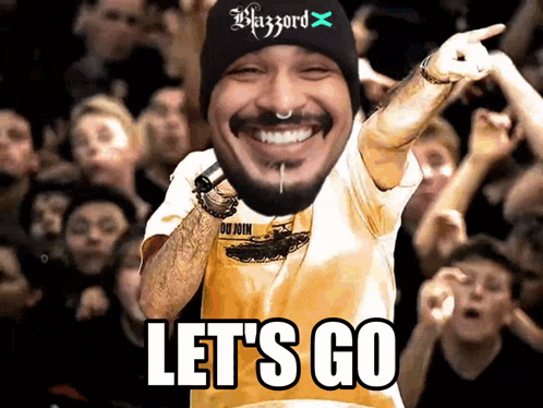 a man wearing a black beanie and a yellow shirt says let 's go in front of a crowd