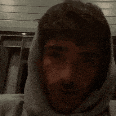 a man with a hood on his head looks to the side