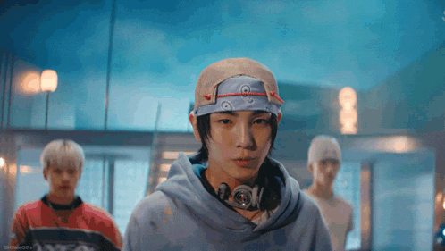 a man wearing a bandana and headphones is standing in a room with other men .