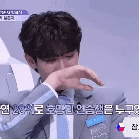 a young man in a suit and tie is crying while covering his mouth with his hand .