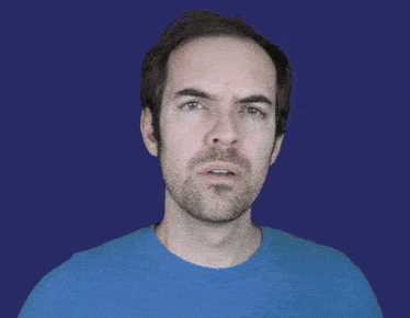 a man with a beard wearing a blue shirt is making a funny face