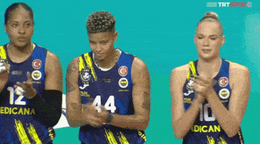 three female basketball players wearing jerseys with the number 12 44 and 10 applauding