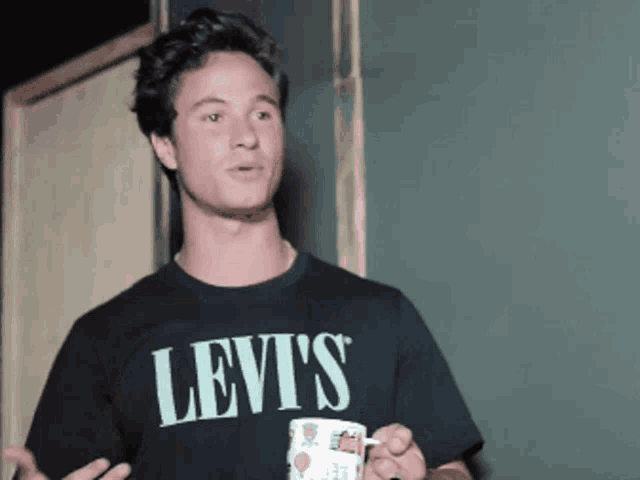 a man wearing a black levis shirt holds a cup