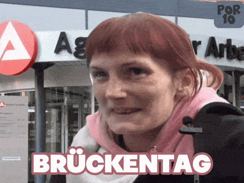 a woman stands in front of a sign that says agr arbeit