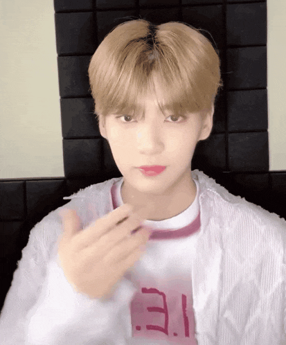 a young man with blonde hair is wearing a white jacket and a pink shirt with the letter e on it