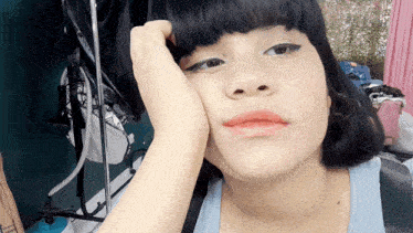 a woman rests her head on her hand in front of a clothes rack