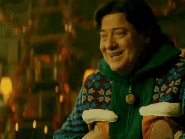 a man wearing a green sweater with a button that says ' a ' on it