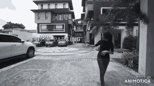 a woman stands in front of a building that has guest parking written on it