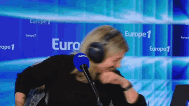 a woman wearing headphones stands in front of a sign that says euro