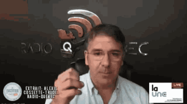 a man is talking into a microphone in front of a sign that says radio