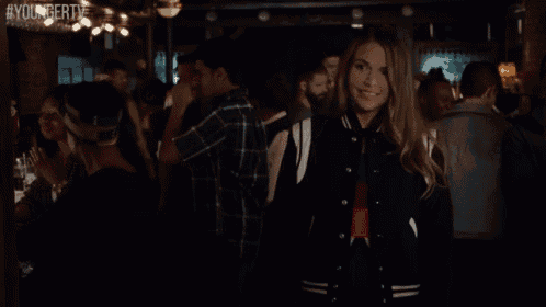 a woman in a black and white jacket is smiling in a crowded room .