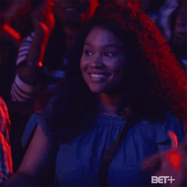a woman giving a thumbs up in a crowd with bet + written on the bottom