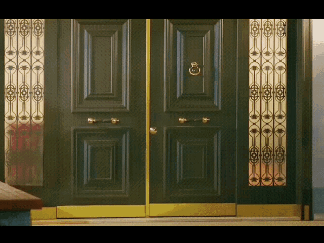 a black door with a gold trim and a door knocker on it