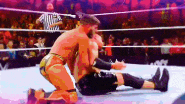two wrestlers are wrestling in a ring with a referee watching