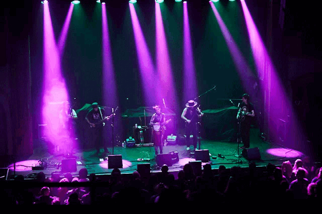 a group of people on a stage with purple lights behind them