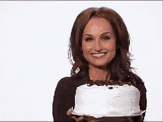 a woman is holding a cake in front of her face and eating it .
