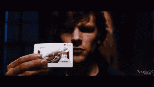a close up of a man holding a joker playing card in his hand