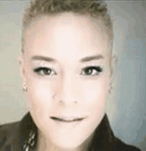 a close up of a woman 's face with a shaved head and curly hair .