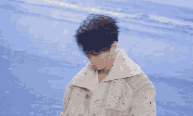 a young man wearing a white sweater and white shirt