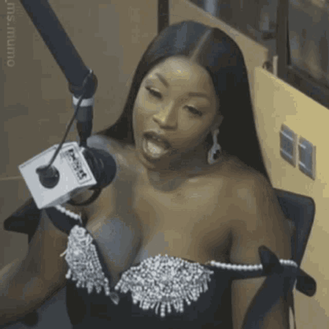 a woman in a black dress is talking into a microphone that says nbc on it