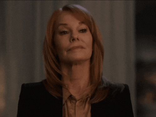 a woman with red hair is wearing a black jacket and a brown shirt