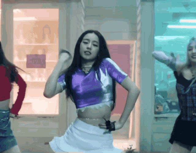 a woman in a purple top and white skirt is dancing in front of a sign that says ' studio '