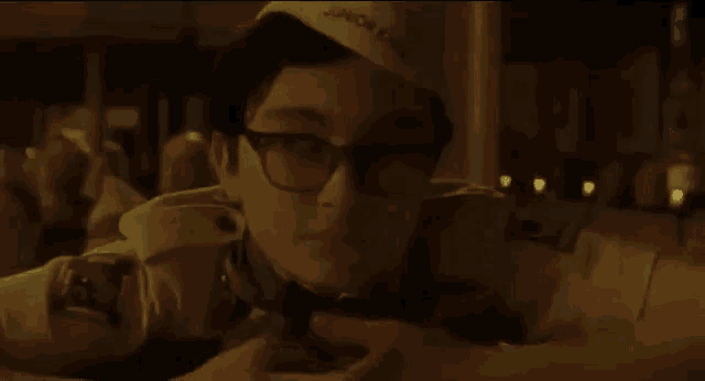 a young boy wearing glasses and a hat is laying down on the floor .
