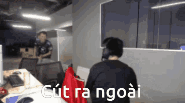 a man wearing headphones is standing in front of a wall that says cut ra ngoai