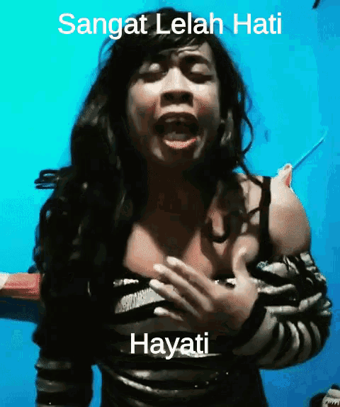 a woman singing in front of a blue wall with the words sangat lelah hati hayati
