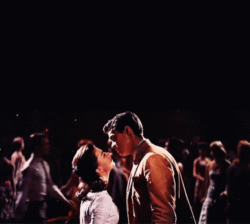 a man and woman kissing in front of a crowd of people