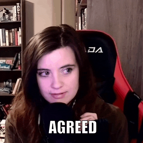 a woman is sitting in a chair with a microphone in front of her and the word agreed is on her face .